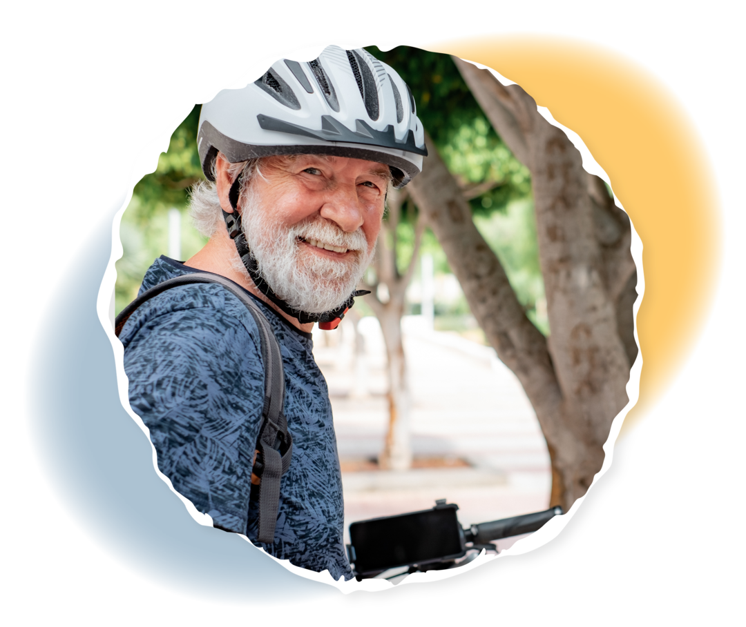 Ein älterer Mann mit Fahrradhelm lächelt in die Kamera.